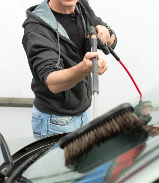 Car washing. Man cleaning car using high pressure water and brush outdoor