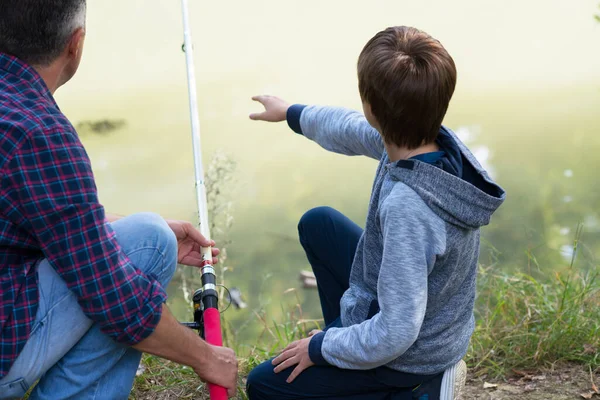 川の銀行 夏の屋外で息子釣りと父 男と若い男の子がロッドと釣りで川の岸に立っている 家族のレジャー 子育て 釣りだ 天使よ — ストック写真
