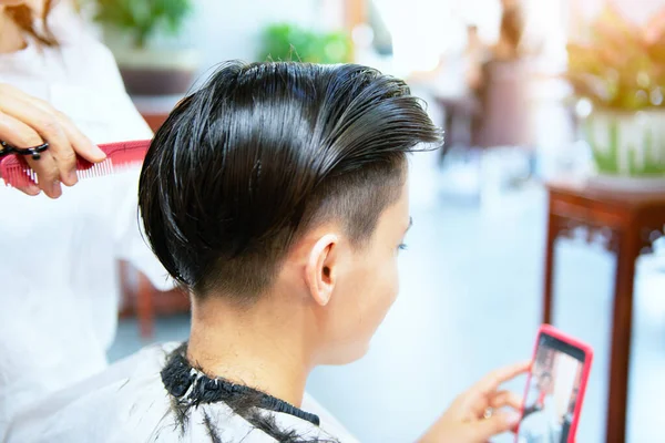 Beauty, hairstyle, treatment, hair care concept, young woman and hairdresser cutting hair at hairdressing salon. Hairdresser cutts beautiful happy girl's hair. Hairstylist serving client at barber shop. Professional barber doing hairstyle in barbersh