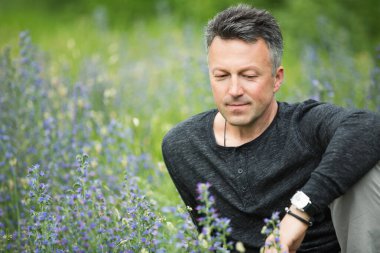 Yaz otlağında poz veren yakışıklı, orta yaşlı bir adamın portresi..