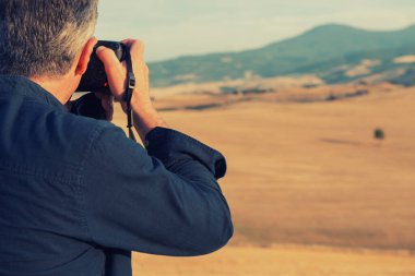 Profesyonel fotoğrafçı dijital kamerayla tarlaların ve dağların fotoğraflarını çekiyor, İtalya, Toskana, Avrupa. 