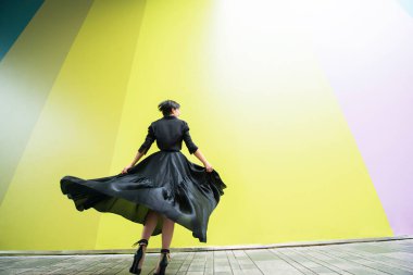 Moda kadını. Genç, güzel Çinli kız dışarıda dans ediyor uzun siyah elbiseler giyiyor ve yüksek topuklu ayakkabılar giyiyor. Modaya uygun bir bayan.. 