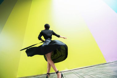 Moda kadını. Genç, güzel Çinli kız dışarıda dans ediyor uzun siyah elbiseler giyiyor ve yüksek topuklu ayakkabılar giyiyor. Modaya uygun bir bayan.. 