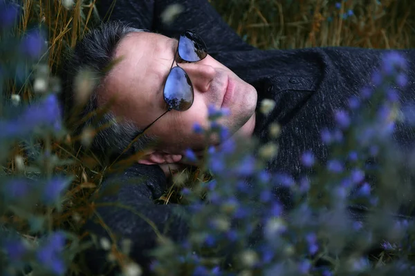 Portret Przystojnego Mężczyzny Średnim Wieku Leżącego Polu Pośród Niebieskich Kwiatów — Zdjęcie stockowe