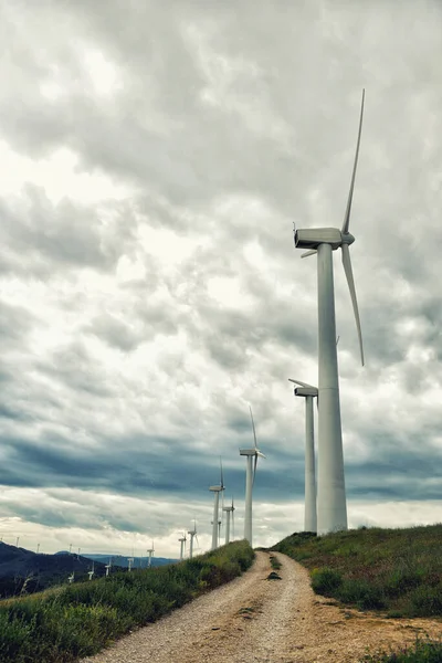 Wind turbines. Wind generators. Wind turbine generators. Alternative energy. Windmills over dramatic cloudy sky. Industrial landscape. Windmill generator. Vertical wind turbines