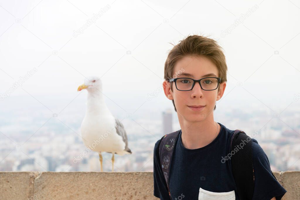 Handsome teen boy and albatross over background of panorama of Alicante (Spain). City view from Mount Santa Barbara with bird and teen foreground 