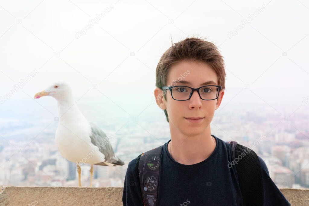 Handsome teen boy and albatross over background of panorama of Alicante (Spain). City view from Mount Santa Barbara with bird and teen foreground 