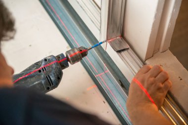 Erkek işçi, alçıpan, dekor ve matkap için profil oluşturarak çalışır. İnşaat işleri, tamirat. Yenileme