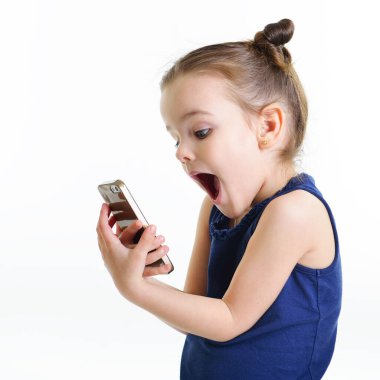 Akıllı telefonla fotoğraf çeken neşeli küçük bir kızın portresi. Beyaz arka planda izole edilmiş ön kamerada selfie çeken sevimli bir çocuk. Cep telefonu kullanan çocuk.