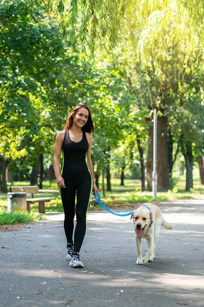 快乐的年轻女子和她的狗在夏天的公园里散步和跑步 活动休闲 美丽的黑发女孩在早晨慢跑与小狗 — 图库照片