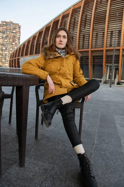 Fashion model sitting and posing outdoor. Young blond caucasian woman posing winter outdoor. Beautiful girl, urban portrait in Milan, Italy