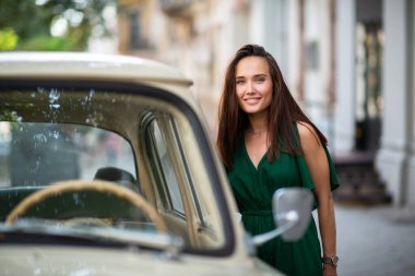 Sovyet klasik arabasının yanında yeşil giyimli, açık havada poz veren manken. Genç, güzel esmer, beyaz kadın yaz sokaklarında yürüyor. Güzel kız, şehir portresi..
