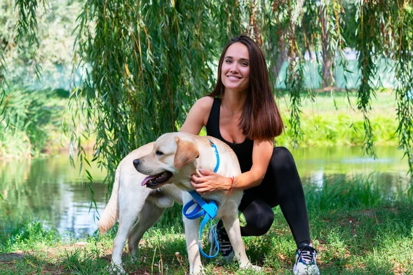 Fröhliche Hübsche Junge Frau Sitzt Und Umarmt Ihren Hund Flussufer — Stockfoto