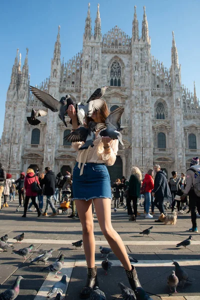 Young attractive woman posing with pigeon near Milan Cathedral (Duomo di Milano), Italy.