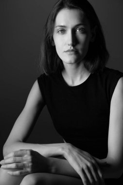 Moda modeli. Stüdyoda siyah elbiseler giymiş genç bir kadının portresi. Gri arka planda güzel beyaz bir kız. Siyah ve beyaz