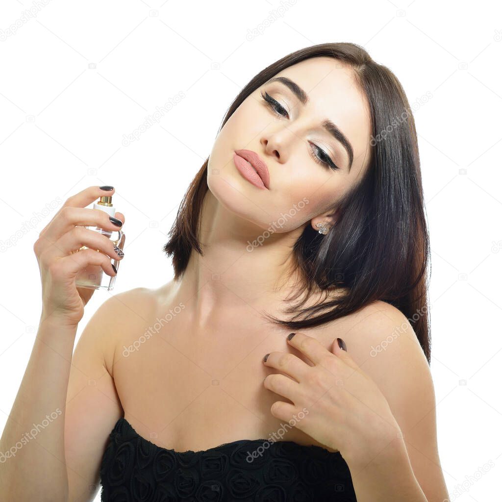 Girl with perfume, young beautiful woman holding bottle of perfume and smelling aroma. Pretty lady posing with a bottle of expensive perfume