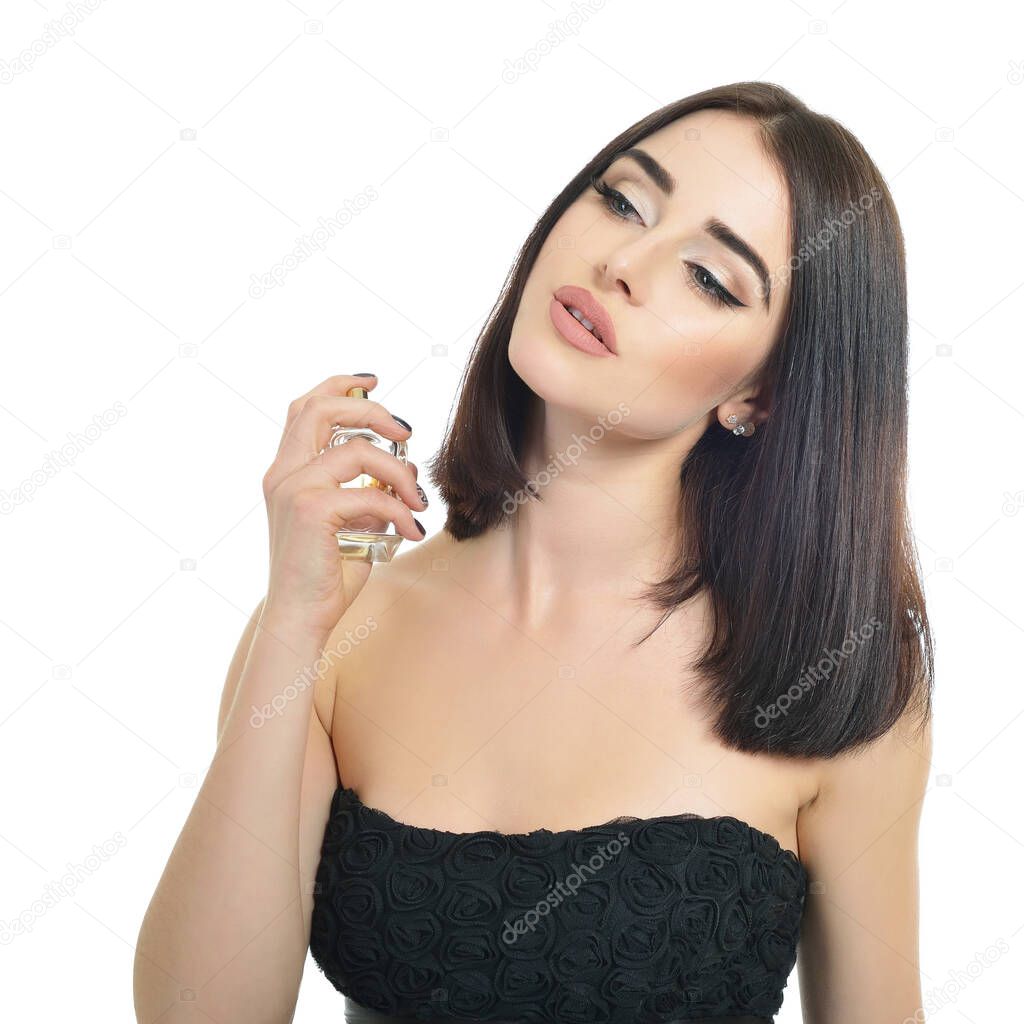Girl with perfume, young beautiful woman holding bottle of perfume and smelling aroma. Pretty lady posing with a bottle of expensive perfume