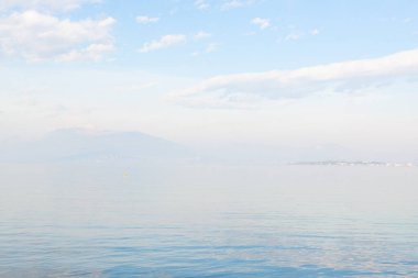 Desenzano del Garda, İtalya. İtalyan Gölü 'nün sakin manzarası Garda. Suyla, gökyüzüyle ve dağlarıyla sisli muhteşem bir manzara. Etrafı dağlarla çevrili muhteşem Garda Gölü manzarası. Yeryüzündeki cennet.