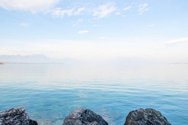 Desenzano del Garda, İtalya. İtalyan Gölü 'nün sakin manzarası Garda. Suyla, gökyüzüyle ve dağlarıyla sisli muhteşem bir manzara. Etrafı dağlarla çevrili muhteşem Garda Gölü manzarası. Yeryüzündeki cennet.