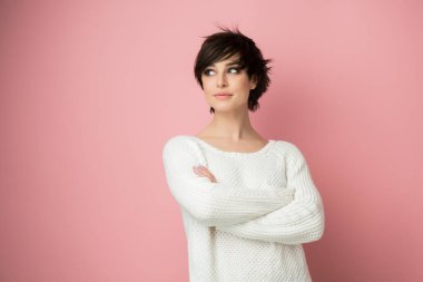 Stüdyoda pembe arka planda poz veren genç ve güzel bir bayan. Güzel esmer kadın portresi. Kız düşünür, hayal eder, gelecek için planlar yapar.