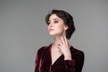 Güzel kadın portresi. Stüdyoda gri arka planda poz veren çekici genç bir kadın. Mükemmel makyajlı güzel bir manken akşam elbisesi giymiş kameraya bakıyor..