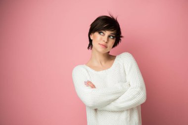 Stüdyoda pembe arka planda poz veren genç ve güzel bir bayan. Güzel esmer kadın portresi. Kız düşünür, hayal eder, gelecek için planlar yapar.