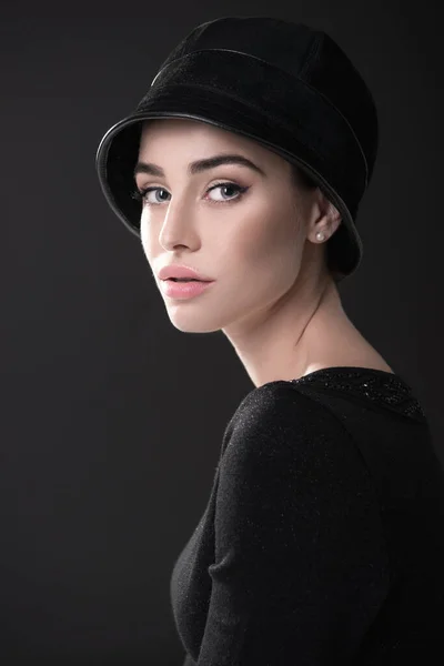 Fashion woman. Black and white portrait of beautiful young elegant lady in black dress and hat. Vintage styling. Beauty, fashion, style