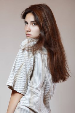 Moda modeli. Stüdyoda poz veren genç bir kadın. Gri arka planda güzel beyaz kız, görüntü tonlu..