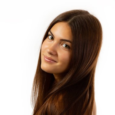 Sağlıklı doğal ciltli, dişi yüzünün güzel bir portresi. Uzun kahverengi saçlı güzel bronzlaşmış genç kız kameraya bakıyor. Stüdyoda poz veren oldukça çekici genç bir kadın.