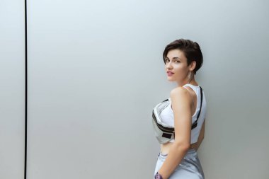 Gümüş metal arka plan duvarında poz veren çekici genç bir kadın. Güzel kız. Güzel beyaz model portresi. Kadın modası ya da bekar kadın erkek konsepti arıyor.