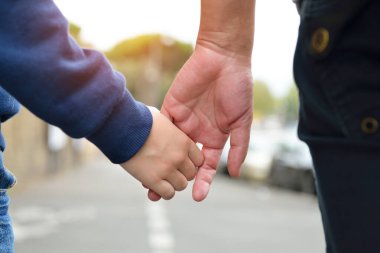 Çocuk ve kadın elleri yakın çekim. Anne, küçük oğlunu, şehir dışını, güven ailesini, çocukluğu ve ebeveynlik kavramını yönetiyor.. 