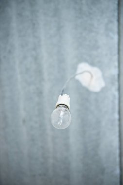 Parlayan lamba. Tavanda eski bir ampul var. Boş bir dairede biri tamirat yapıyor.