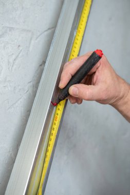 Erkek işçi alçıpan için profil, kesim işaretleri için çalışıyor. İnşaat işleri, tamirat. Yenileme