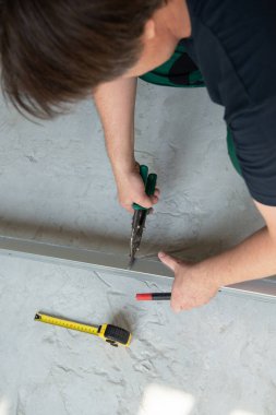 Erkek işçi alçıpan için profil oluşturup metal makasla kesiyor. İnşaat işleri, tamirat. Yenileme