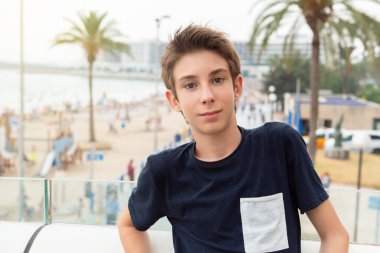 Alicante panoramasının üzerinden denize bakan gözlüklü yakışıklı bir genç. İspanya 'nın Akdeniz kıyısında gülümseyen güzel bir genç çocuk. Seyahat, yaz tatili, turizm, gençlik yaşam tarzı.