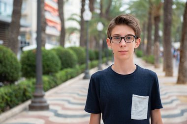 Alicante 'nin panoramasından kameraya bakan gözlüklü yakışıklı bir genç. İspanya 'nın Akdeniz kıyısında gülümseyen güzel bir genç çocuk. Seyahat, yaz tatili, turizm, gençlik yaşam tarzı.
