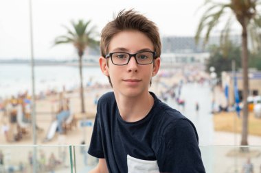 Alicante panoramasının üzerinden denize bakan gözlüklü yakışıklı bir genç. İspanya 'nın Akdeniz kıyısında gülümseyen güzel bir genç çocuk. Seyahat, yaz tatili, turizm, gençlik yaşam tarzı.