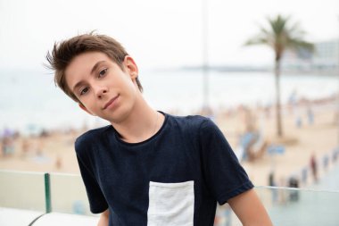 Yakışıklı çocuk Alicante panoramasından kameraya bakıyor. İspanya 'nın Akdeniz kıyısında gülümseyen güzel bir genç çocuk. Seyahat, yaz tatili, turizm, gençlik yaşam tarzı.