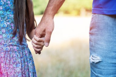 Erkek ve çocuğun elleri. Baba çocuğuna önderlik ediyor, yaz doğası. Ebeveynlik, birliktelik, yardım, birlik, çocukluk, güven, aile kavramı.