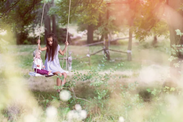 快乐的女孩带着她的复古玩偶在公园里骑着绳子荡秋千 小公主在户外玩的很开心 夏天在户外玩的很开心 儿童生活方式 — 图库照片