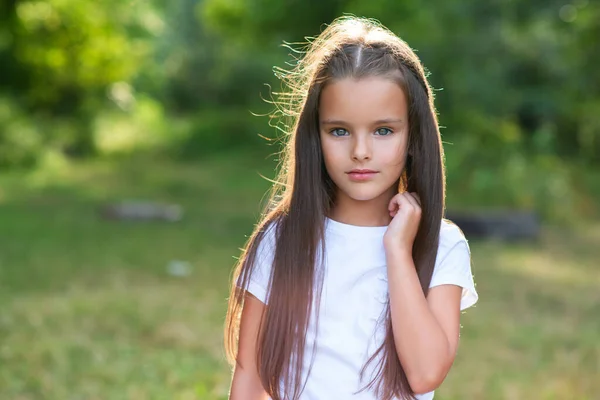 stock image Pretty little girl with long brown hair holding hand near her beautiful face, summer nature outdoor. Kid's portrait. Child's lifestyle