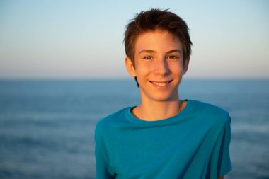 Plajdaki yakışıklı genç çocuk. Akdeniz kıyısında gülümseyen güzel bir genç çocuk. Seyahat, yaz tatili, turizm, gençlik yaşam tarzı.