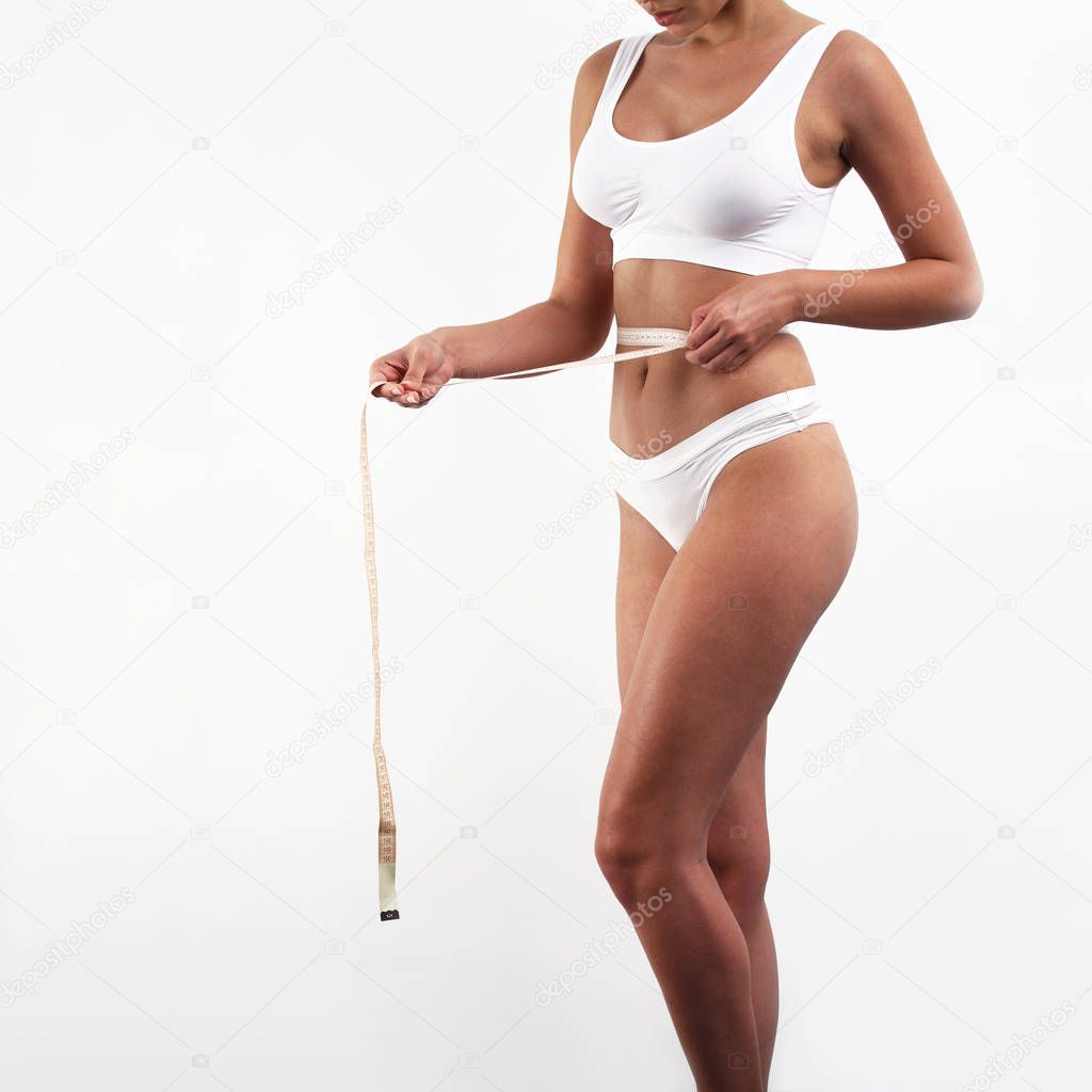 Young woman with tape measure checks her weight loss progress
