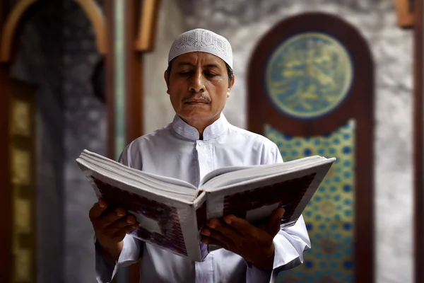 Старый мусульманин читает Коран в мечети — стоковое фото