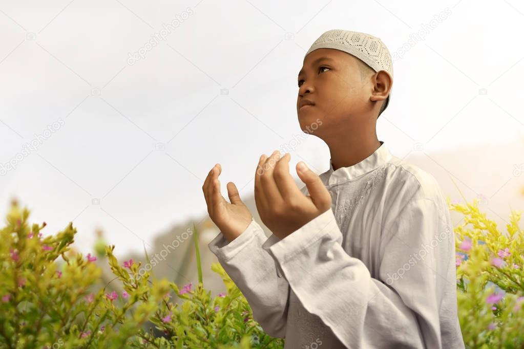 Asian muslim kid praying on garden
