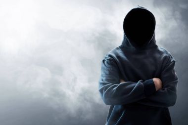 Bilinmeyen kukuletalı bilgisayar korsanı duman arka plan üzerinde