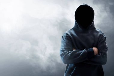 Unknown hooded computer hacker on smoke background clipart
