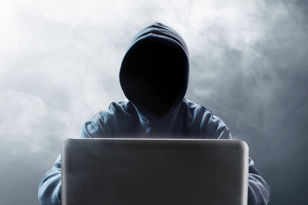 Hacker using laptop on smoke background