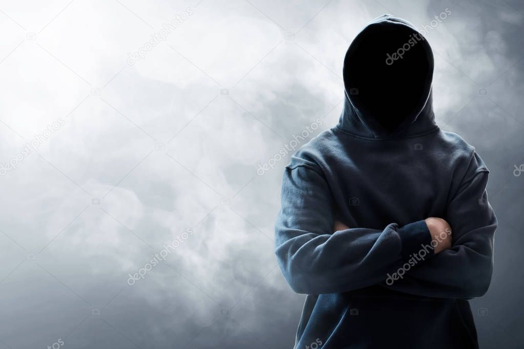 Unknown hooded computer hacker on smoke background