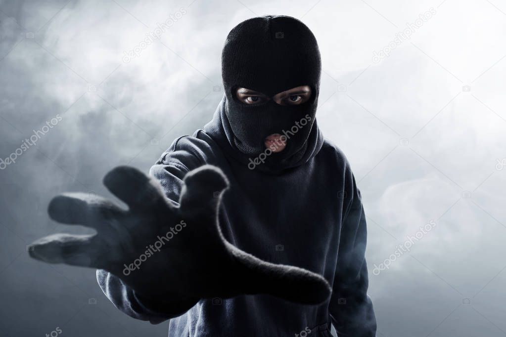 Thief in balaclava on smoke background